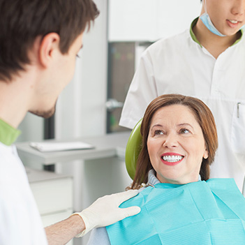 Older woman in dental chair smiling at dentist