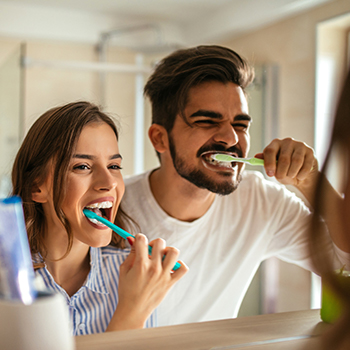 Man and woman brushing teeth together
